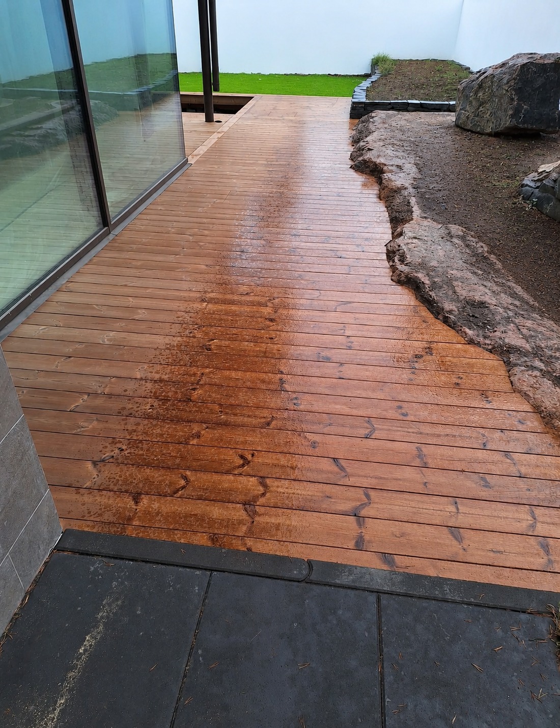 Oiled timber deck along a glass wall in a garden
