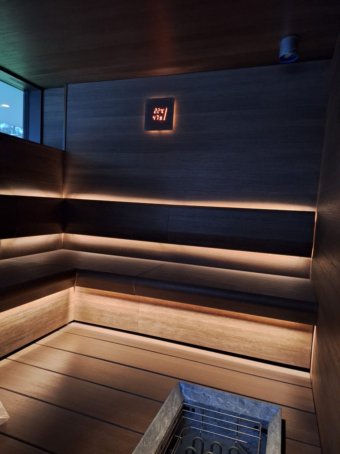 Tumma sauna epäsuoralla LED-valaistuksella ja kiukaalla